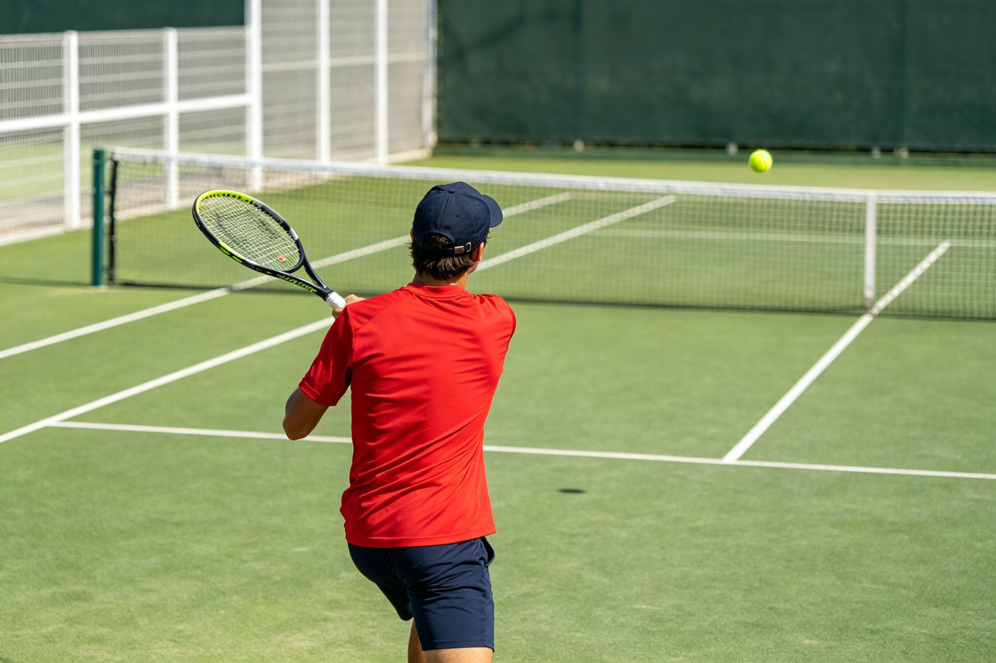 Player hitting a pickleball on an outdoor court wearing RedLake gear